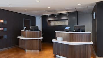 A reception area with two curved reception desks, a wall-mounted screen, and a wooden floor.
