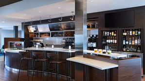 Un espace bar moderne doté d’un îlot central, de tabourets de bar et d’une variété de bouteilles d’alcool.