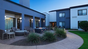 A modern outdoor patio area with a fire pit, seating, and a well-maintained garden.