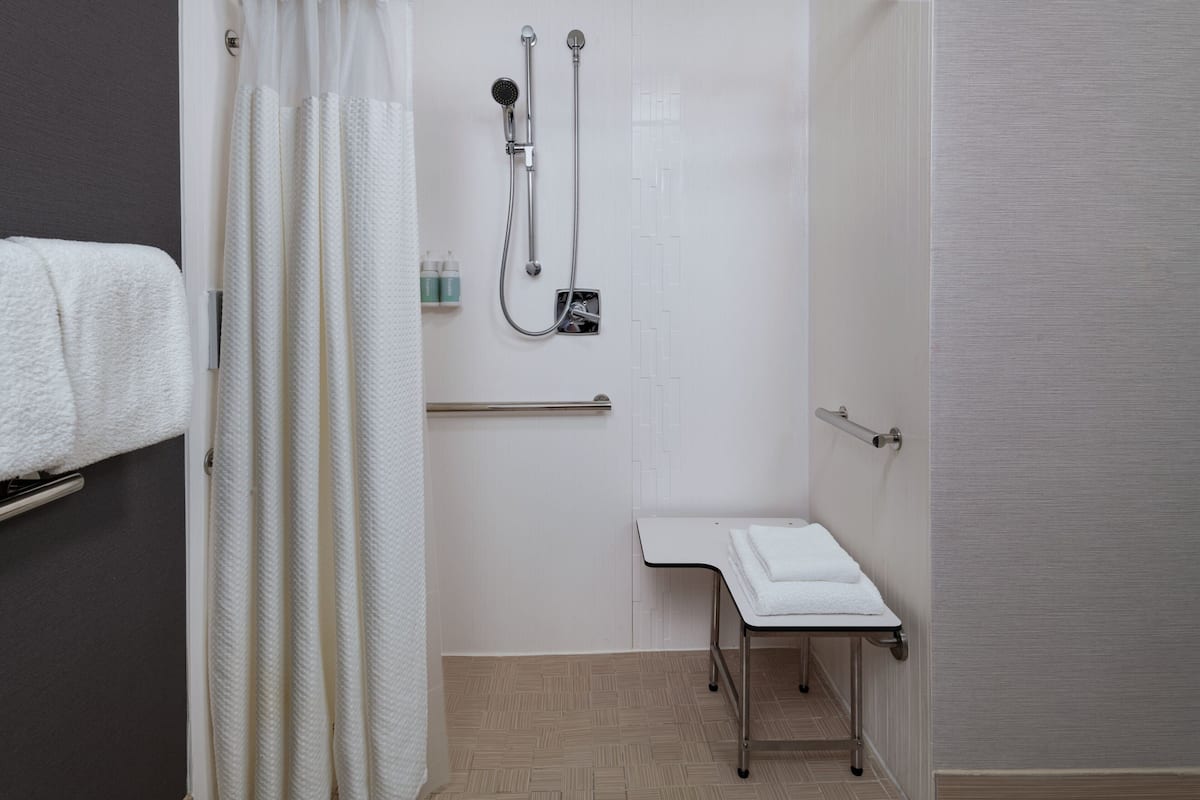 A modern bathroom with a shower, a sink, and a towel rack.