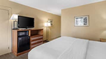 Une chambre d’hôtel équipée d’un lit, d’une télévision, d’un four à micro-ondes, d’une lampe et d’un tableau encadré au mur.
