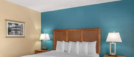 A neatly made bed with white linens, two bedside tables with lamps, and a framed picture on the wall.