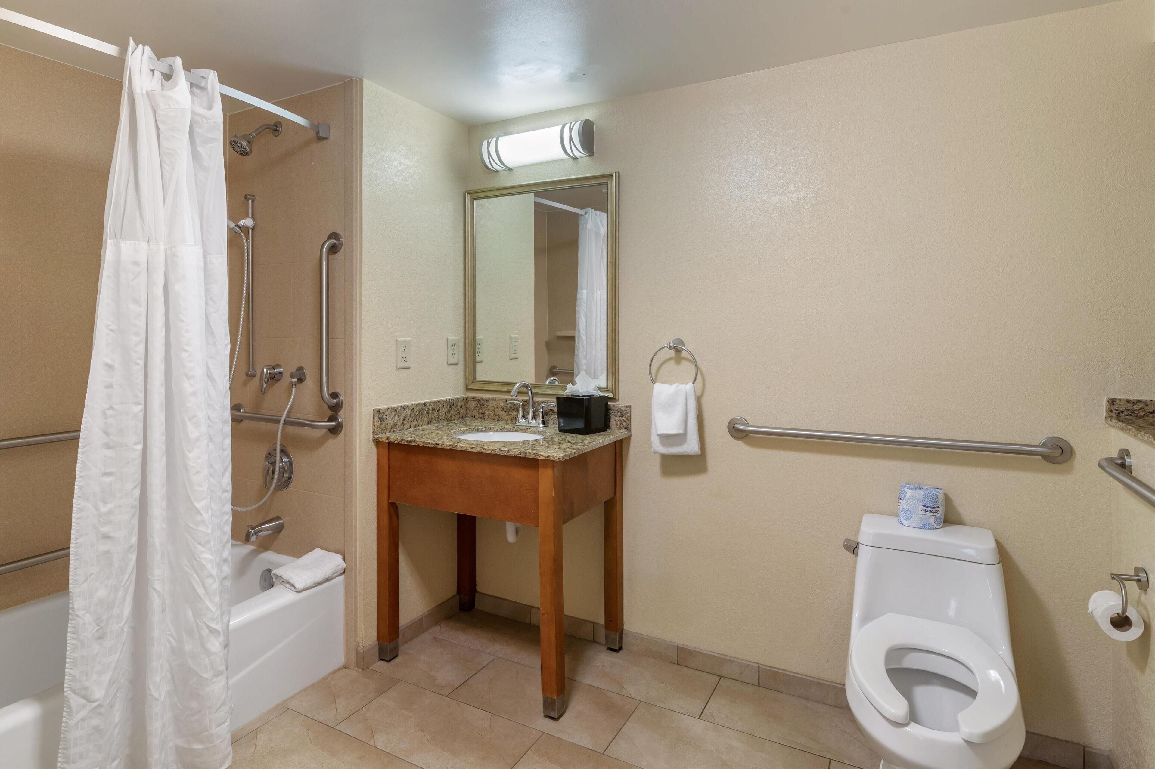 Un baño con ducha, lavamanos, inodoro y espejo.