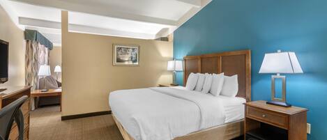 Una habitación de hotel con cama, mesitas de noche, escritorio, silla y televisor.