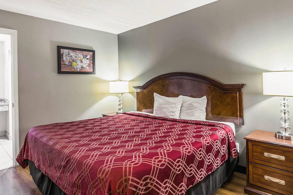 A neatly made bed with a patterned bedspread, a wooden headboard, and two bedside lamps.