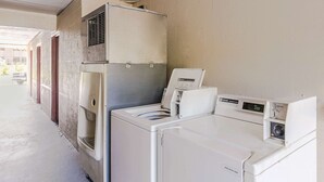 Un área de lavandería con dos lavadoras y una secadora, piso de concreto y una puerta que da a un espacio exterior.