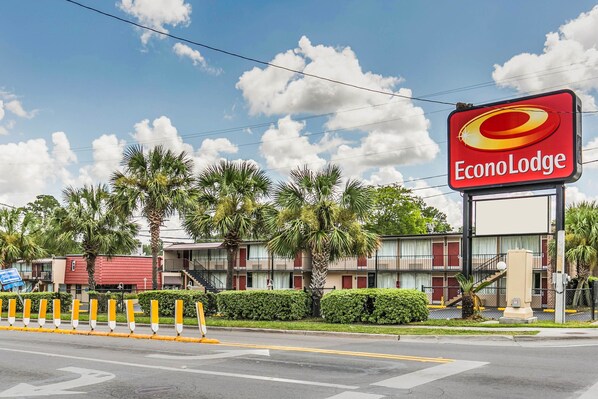 Welcome to EconoLodge, a hotel surrounded by lush palm trees and a neatly trimmed hedge.