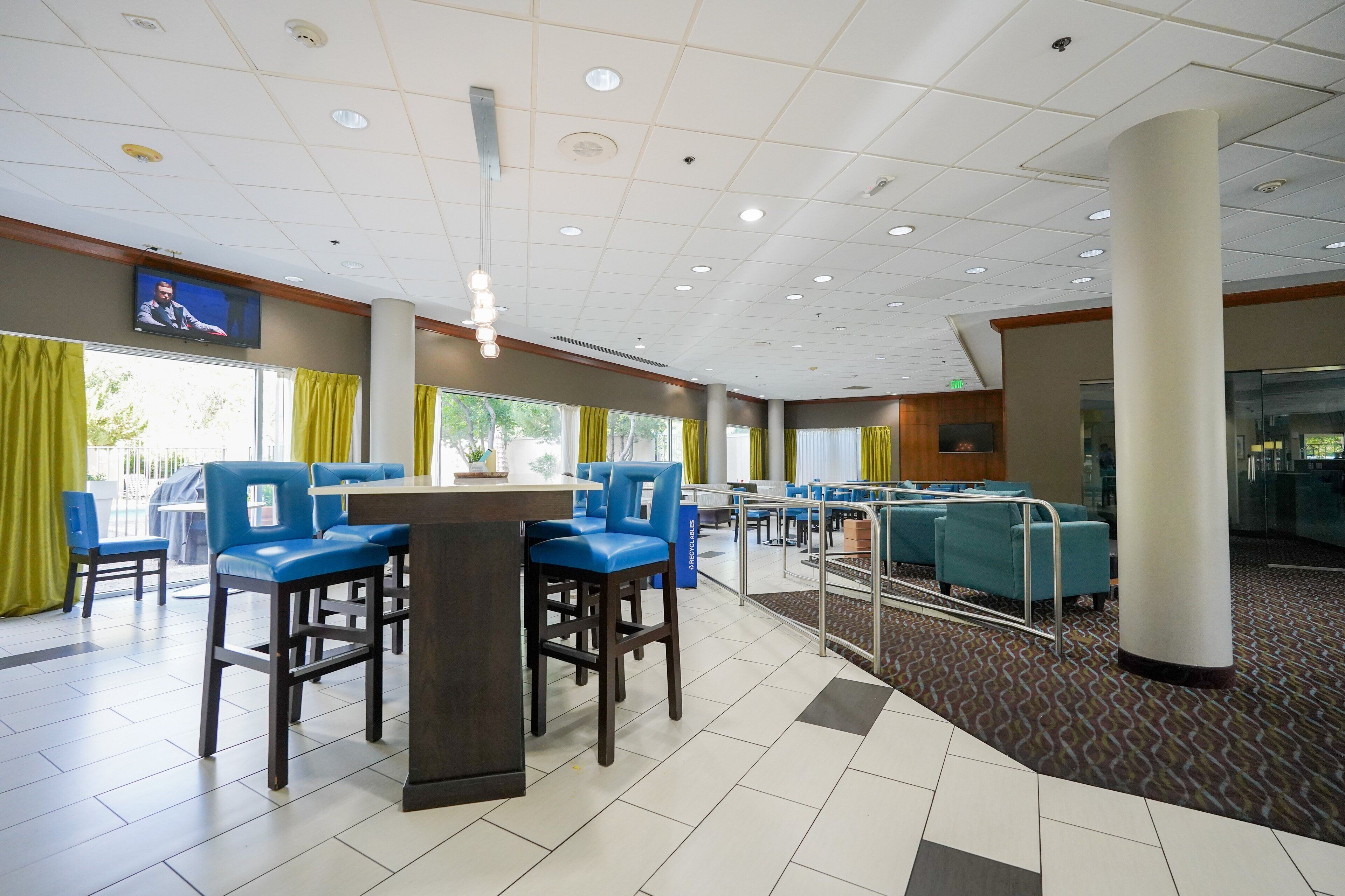 A hotel lobby with a bar area, seating, and a television screen.