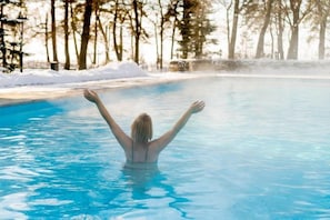 A person in a swimming pool with arms raised, surrounded by trees and snow. - Holiday Inn Express Boise - University Area by IHG (Boise)
