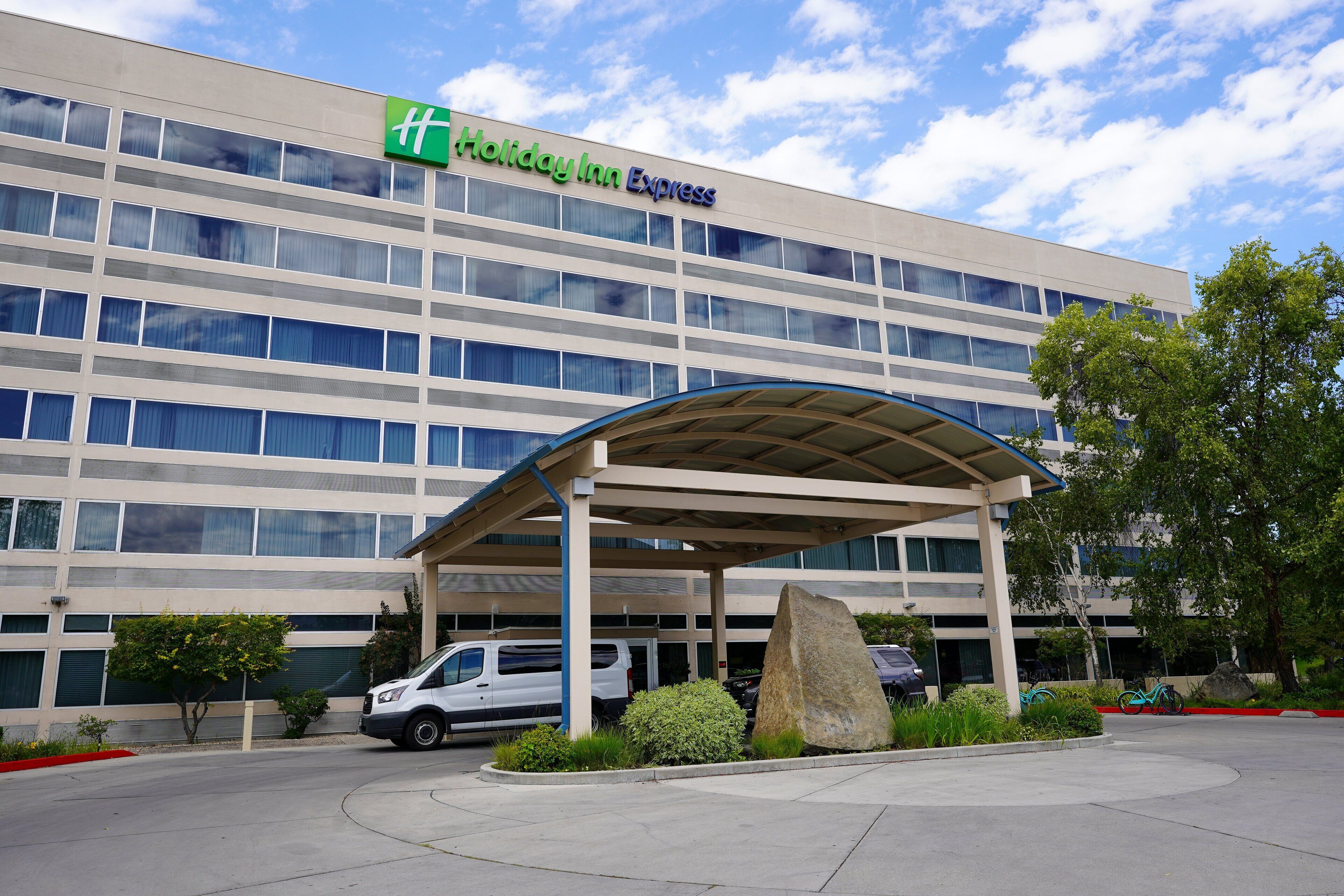 Un hotel Holiday Inn Express con un área de estacionamiento techada y una gran escultura de roca.