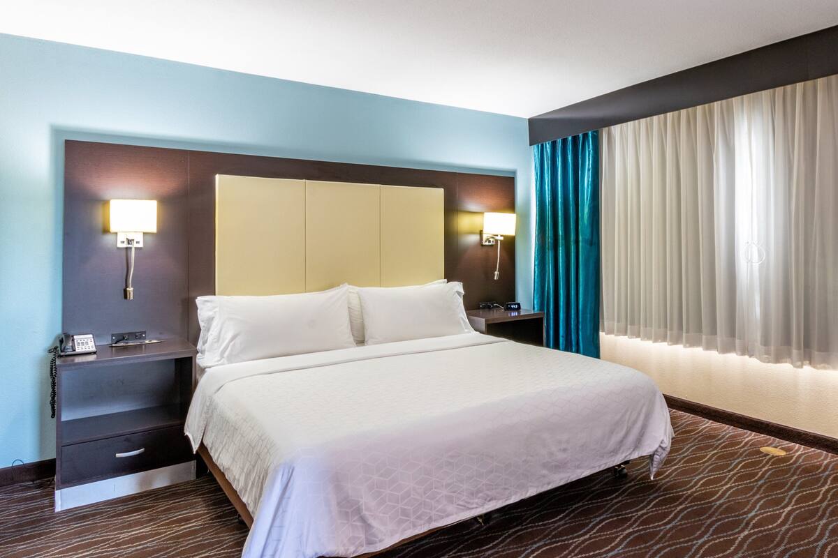 Habitación de hotel con una cama grande, un escritorio, un teléfono y una mesita de noche.