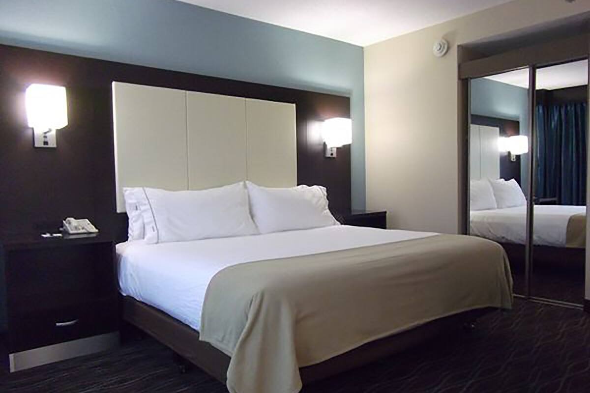 Habitación de hotel con una cama grande, una mesita de noche con teléfono y un espejo que refleja la habitación.