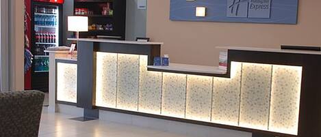 A reception area with a counter, a Coca-Cola refrigerator, and a wall-mounted sign.
