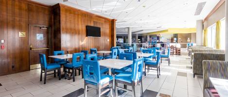 A spacious hotel lobby with a modern design, featuring a mix of seating areas and a central bar.