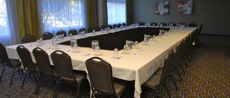A conference room with a long table, chairs, and a carpeted floor.