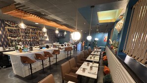 L'intérieur d'un restaurant, avec un bar, des tables et un mur décoratif.