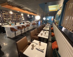 Interior de restaurante con barra, asientos y una pared decorativa.