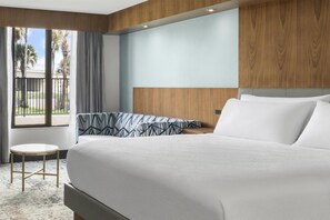 A hotel room with a large bed, a small round table, and a view of palm trees through the window. - Best Western Premier Lakeland North (Lakeland)
