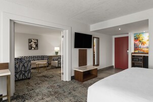 Camera d'albergo con un letto, una televisione, un quadro, un divano, un tavolino da caffè e un bagno.
