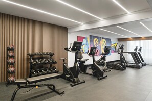 Un gimnasio moderno con diversos equipos de ejercicio, como mancuernas, un banco y máquinas de cardio.