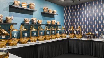 Mesa de buffet com diversos alimentos e douradas tigelas decorativas.