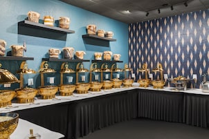 Una mesa de buffet con diversos alimentos y cuencos dorados decorativos.