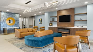 A modern living room with a large sectional sofa, leather armchairs, a flat-screen TV, and a fireplace.