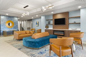Uma sala de estar moderna com um amplo sofá modular, poltronas de couro, uma TV de tela plana e uma lareira.