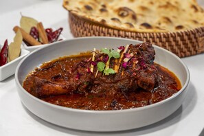 A dish of meat in a sauce, garnished with herbs and spices, served on a white plate. - Best Western Premier Lakeland North (Lakeland)