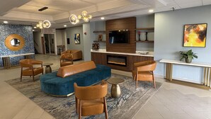 Un salon moderne avec une cheminée, des canapés en cuir et un téléviseur.