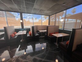 A restaurant with booth seating, large windows, and a polished floor.