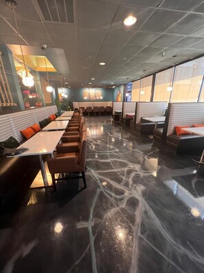 A restaurant with booths and tables, a marble floor, and pendant lighting.