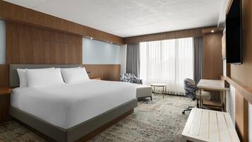 Une chambre d’hôtel avec un grand lit, un bureau, une chaise et un téléviseur.