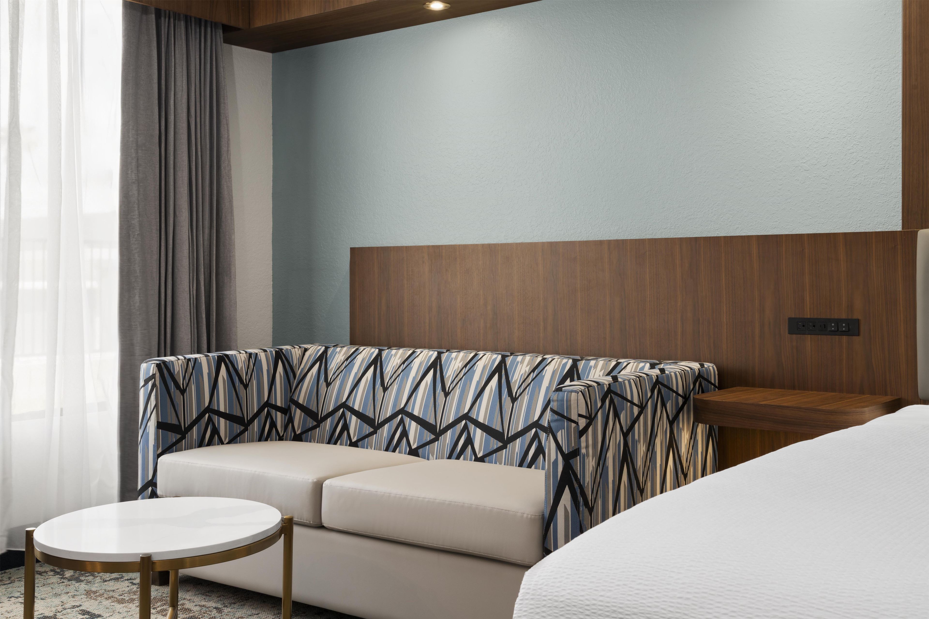 Una habitación de hotel con sofá, una mesa redonda y una cama.