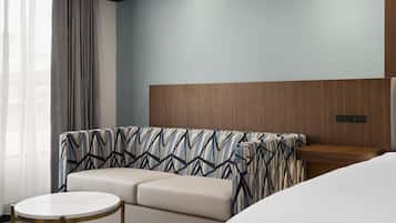 Una habitación de hotel con sofá, una mesa redonda y una cama.