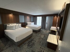 Una habitación de hotel con dos camas, un escritorio pequeño, un espejo y un armario.