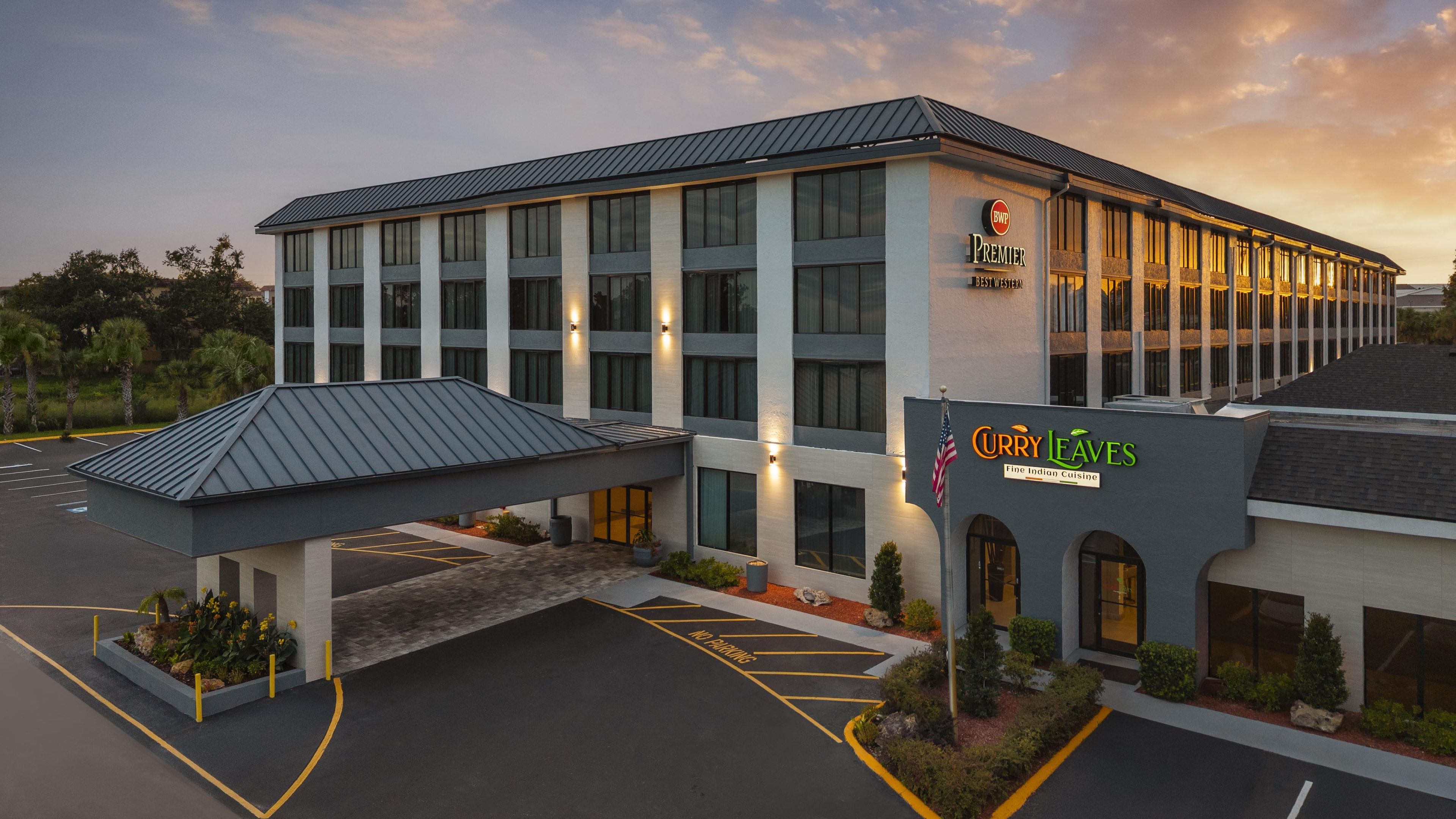 A hotel with a modern design, featuring a prominent entrance and signage for 'Premier Best Western' and 'Curry Leaves Fine Indian Cuisine'.