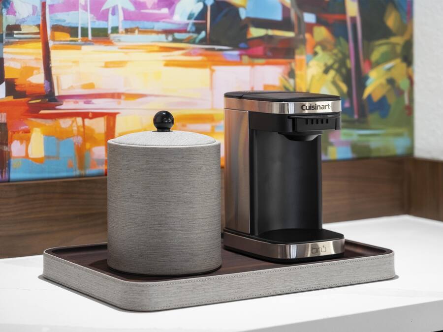 A coffee maker and a cylindrical container on a tray.