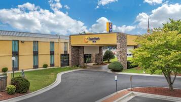 A Comfort Inn hotel with a stone facade, a clear sky, and a well-maintained lawn.