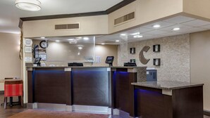 A reception area with a dark wood reception desk, a glass partition, and a clock on the wall. - Comfort Inn Shelby (Shelby)