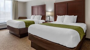 A hotel room with two beds, a desk, a chair, a lamp, and a window with curtains. - Comfort Inn Shelby (Shelby)