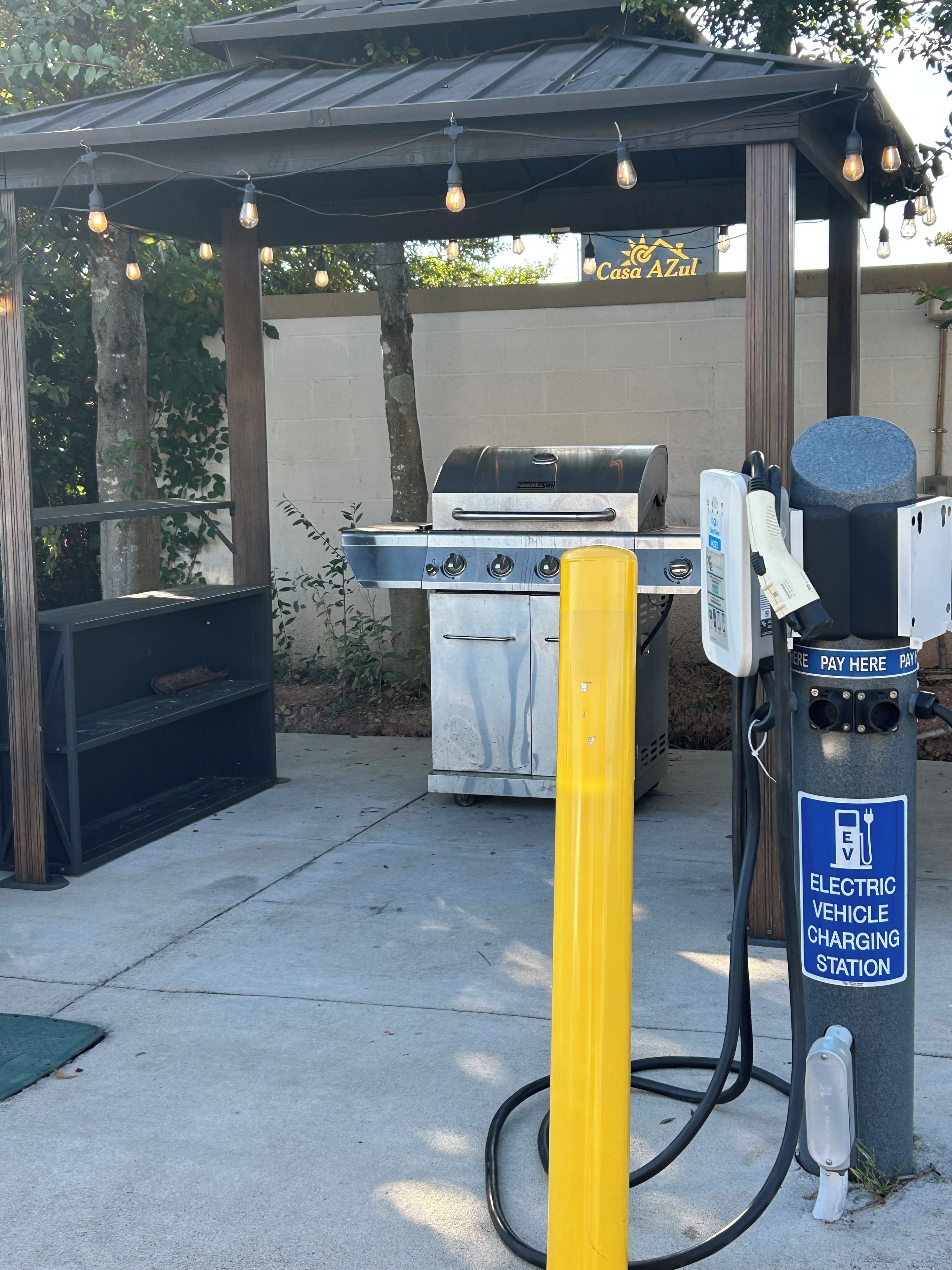 An electric vehicle charging station with a grill and outdoor seating area.