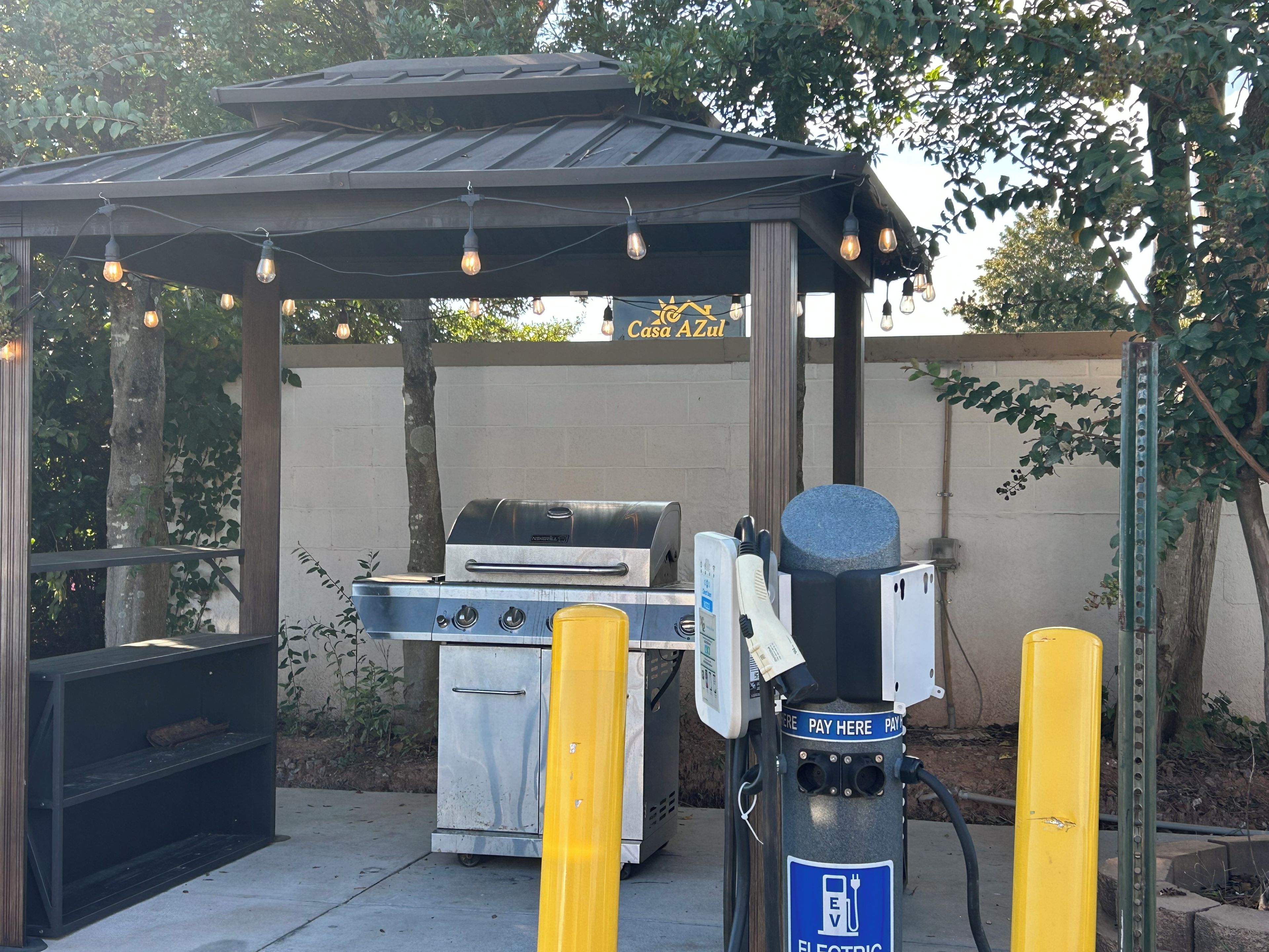 An outdoor electric vehicle charging station with a grill and a covered seating area.