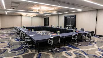 A conference room with a long table, chairs, and a carpeted floor.