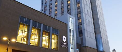 A modern hotel with a prominent entrance, multiple floors, and a clear sky.