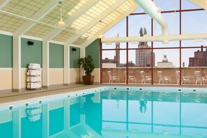 A swimming pool with clear water, a potted plant, and lounge chairs.