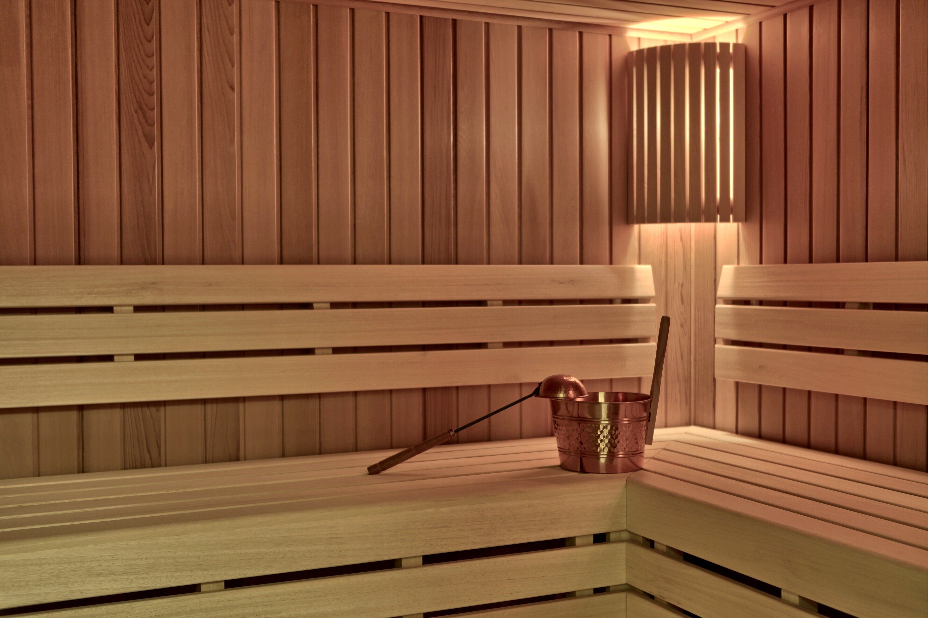 A wooden sauna bench with a copper bucket and a wooden stick.