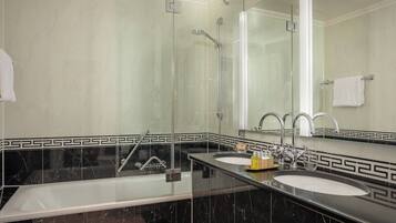 A modern bathroom with a large mirror, two sinks, a shower, and a bathtub.