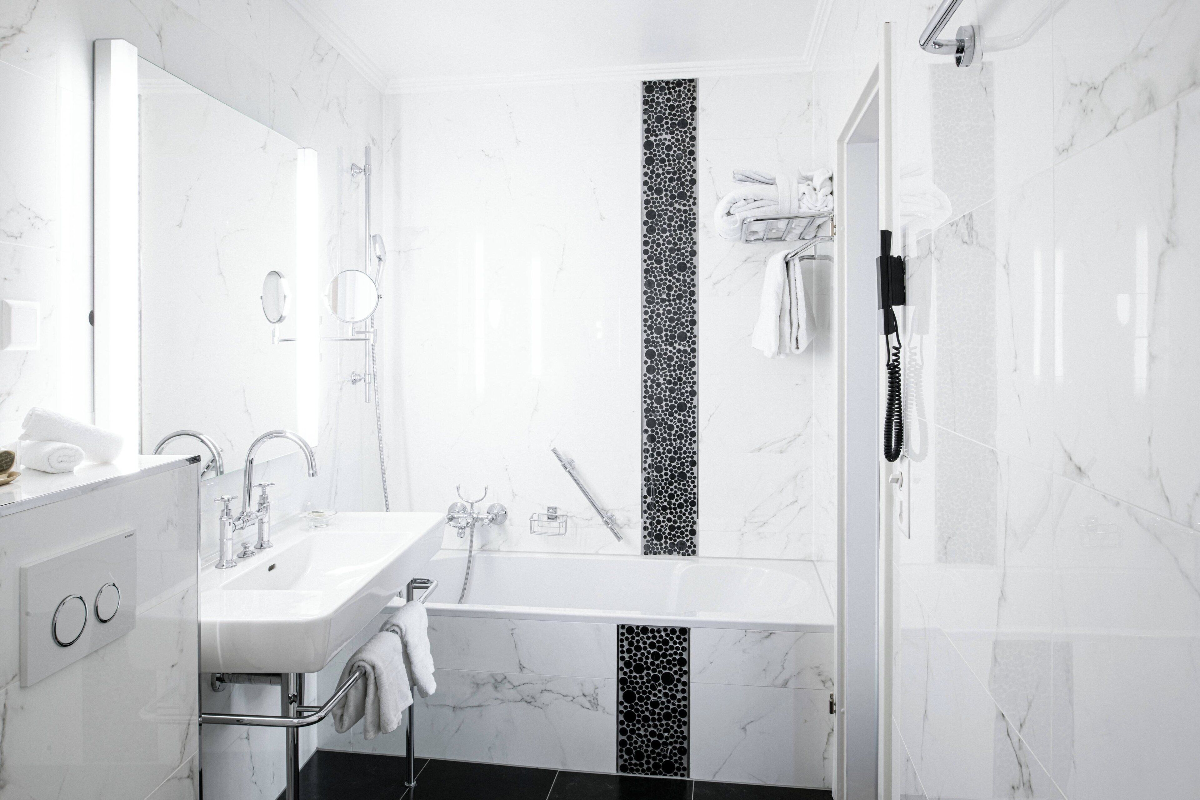 Ein modernes Badezimmer mit einem weißen Marmorwaschbecken, einer Badewanne und einer Dusche.