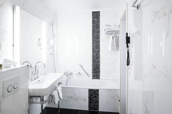 A modern bathroom with a white marble sink, a bathtub, and a shower.